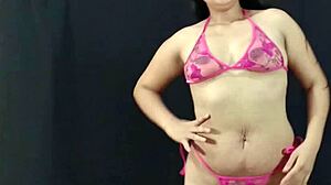 Jonge en ronde Latina schoonheid pronkt met haar bezittingen in roze lingerie en bereidt zich voor op een hete fotoshoot
